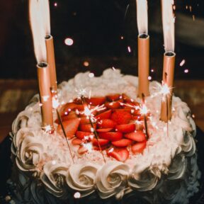 lighted-candles-on-white-icing-covered-cake-1729808